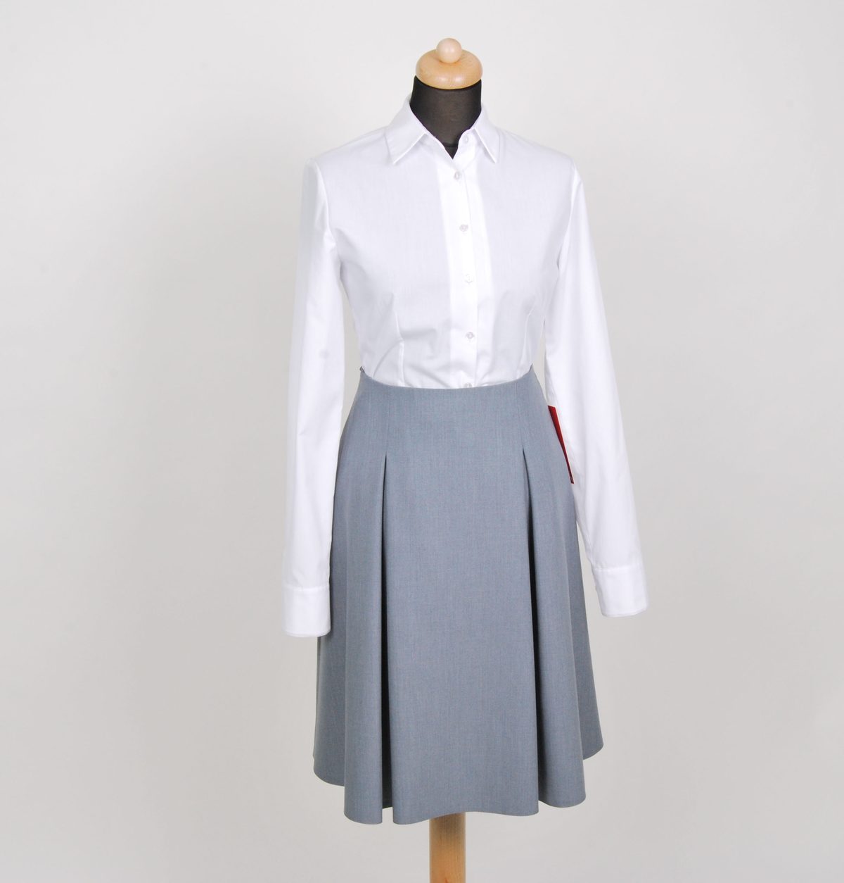 Weiße Bluse mit grauem Faltenrock auf der Schneiderpuppe